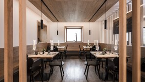 Un espace repas moderne avec un plancher en bois, des chaises noires et des tables dressées avec des serviettes blanches et de la verrerie.