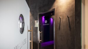 Un couloir avec un panneau indiquant un espace dédié au bien-être et une porte illuminée de lumière violette.
