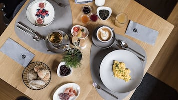 Ett frukostbord med tallrikar fyllda med mat, kaffekoppar och olika sorters tillbehör.