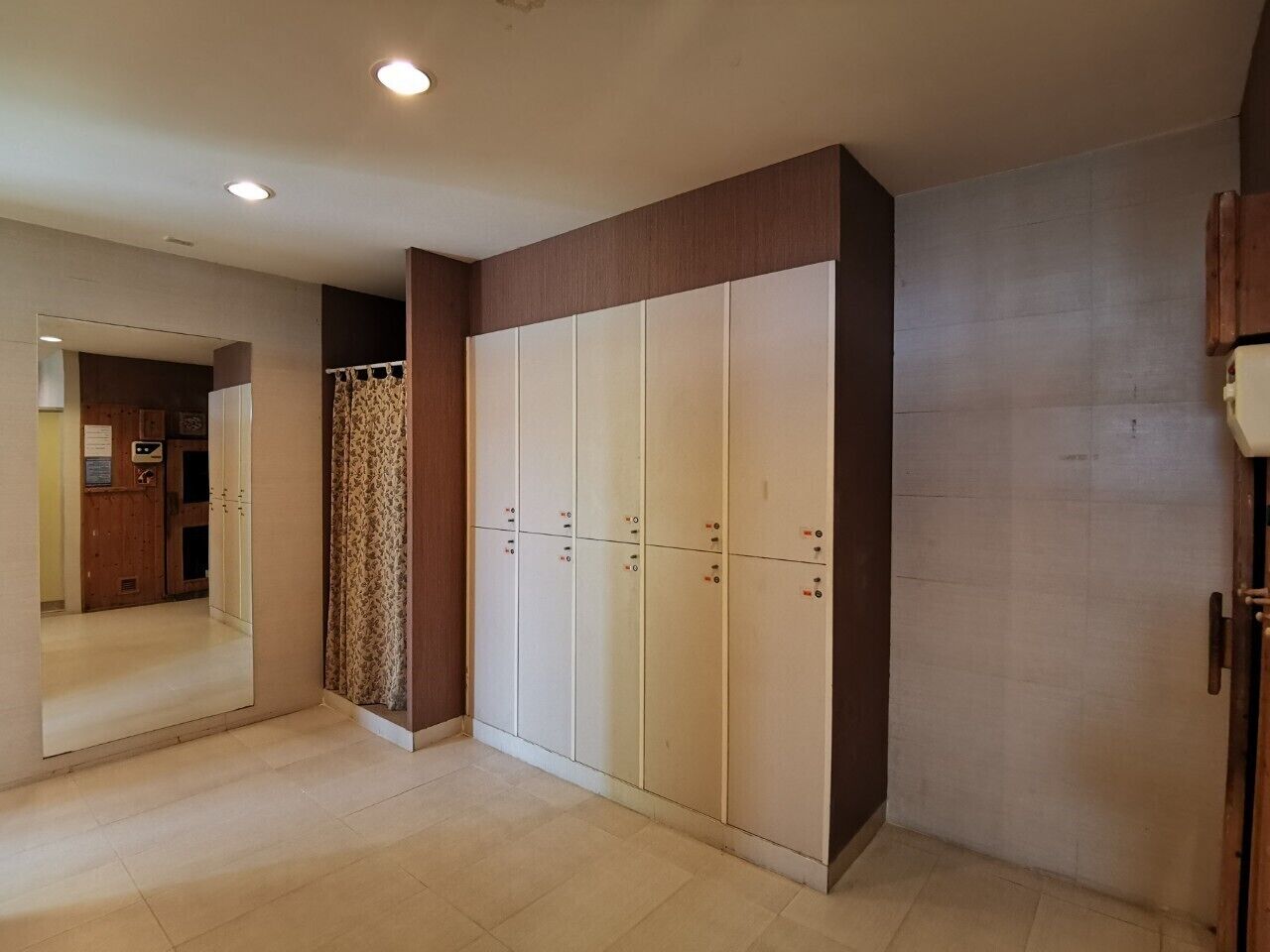 A room with a large wardrobe, a mirror, and a patterned curtain.