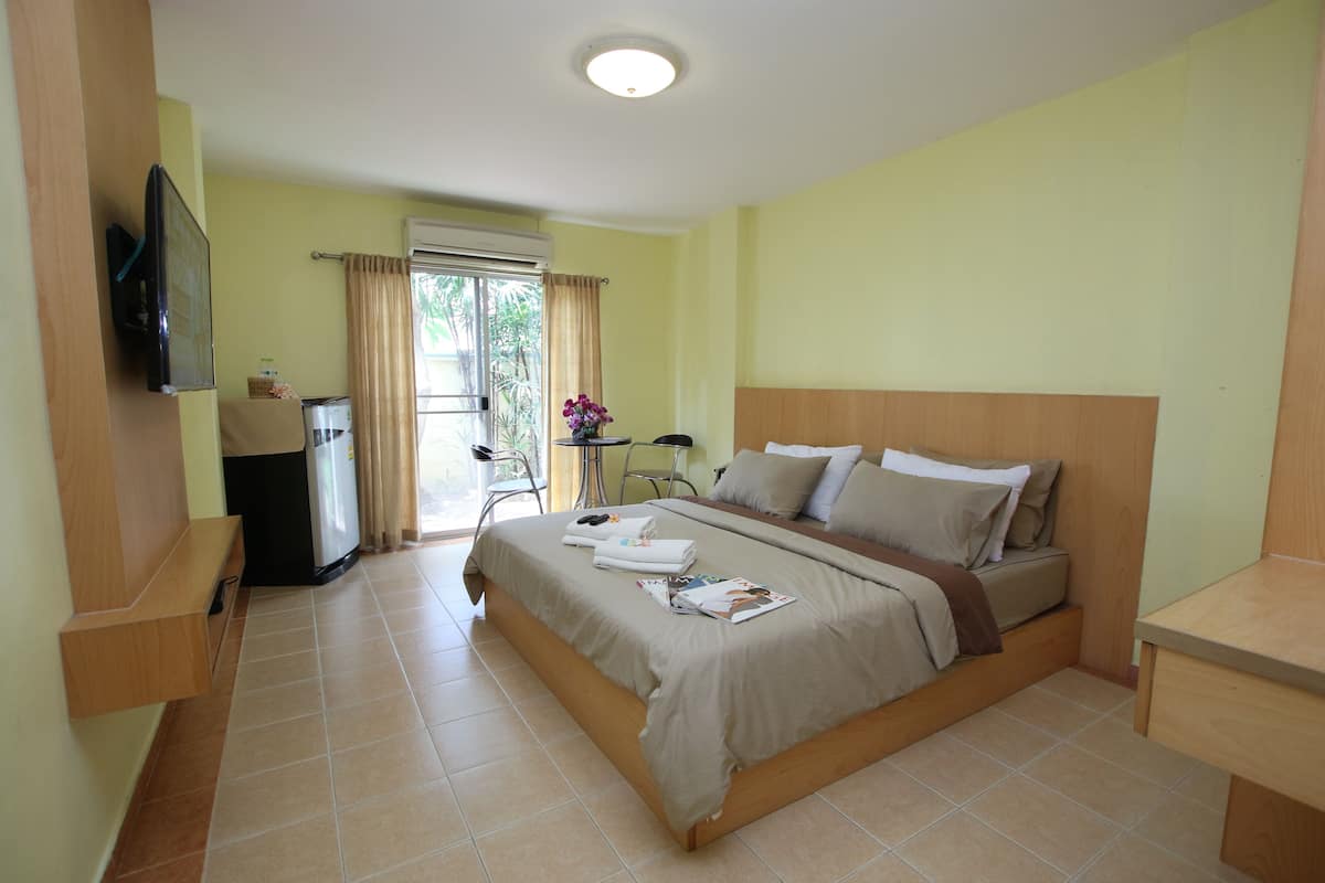 Un dormitorio con una cama, televisor montado en la pared, un escritorio y una silla.