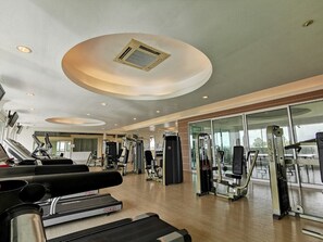 Un gimnasio con cintas de correr, máquinas de pesas y un espejo grande.