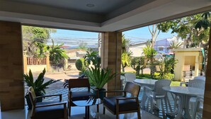 A spacious indoor area with a patio, featuring a glass wall offering a view of the outside. - Suklutai Hotel & Serviced Apartment (Bang Khla)