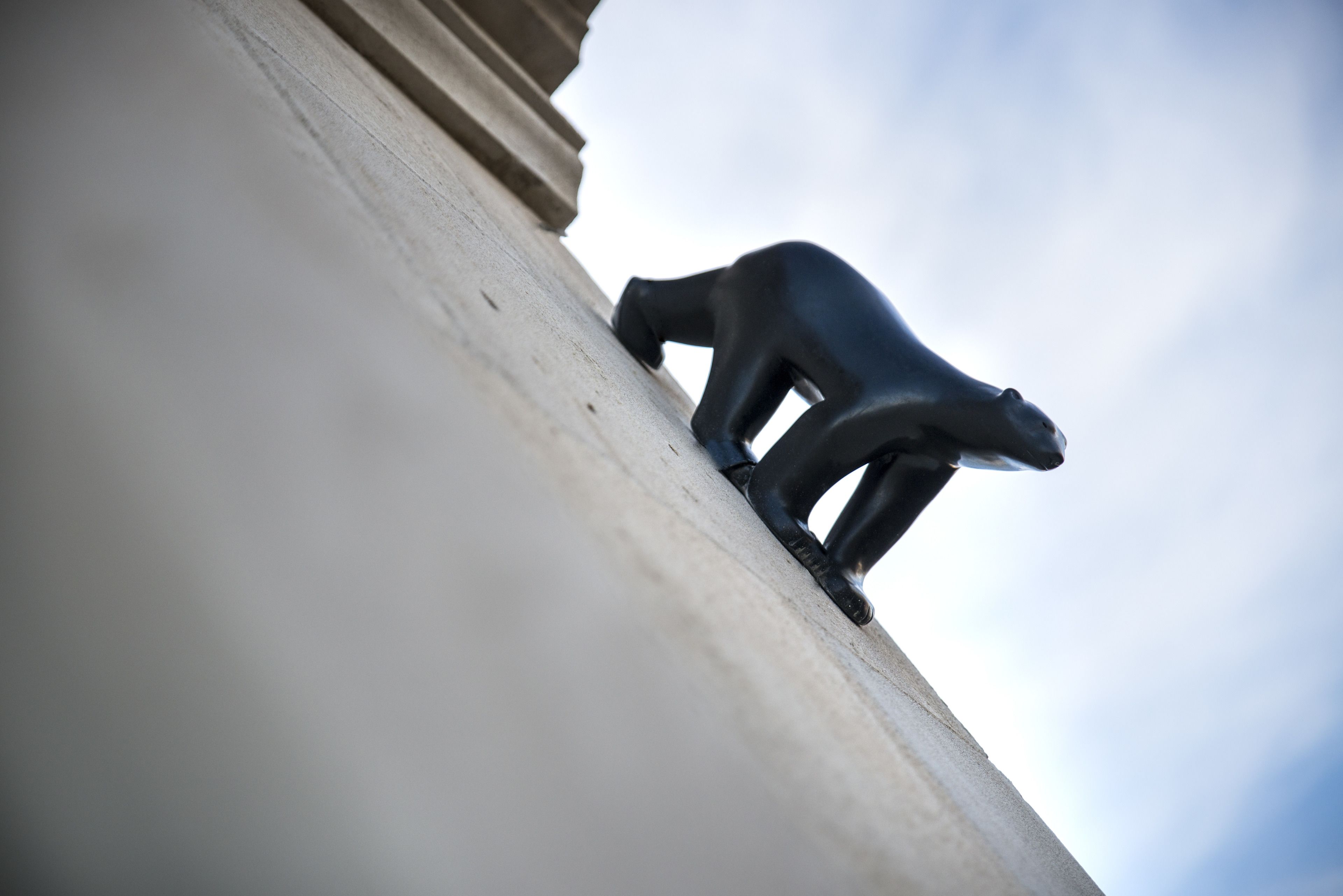 A statue of a bear on a concrete ledge.