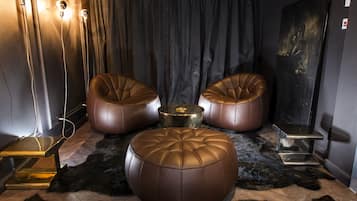 A room with three leather ottomans, a small round table, and a fur rug.