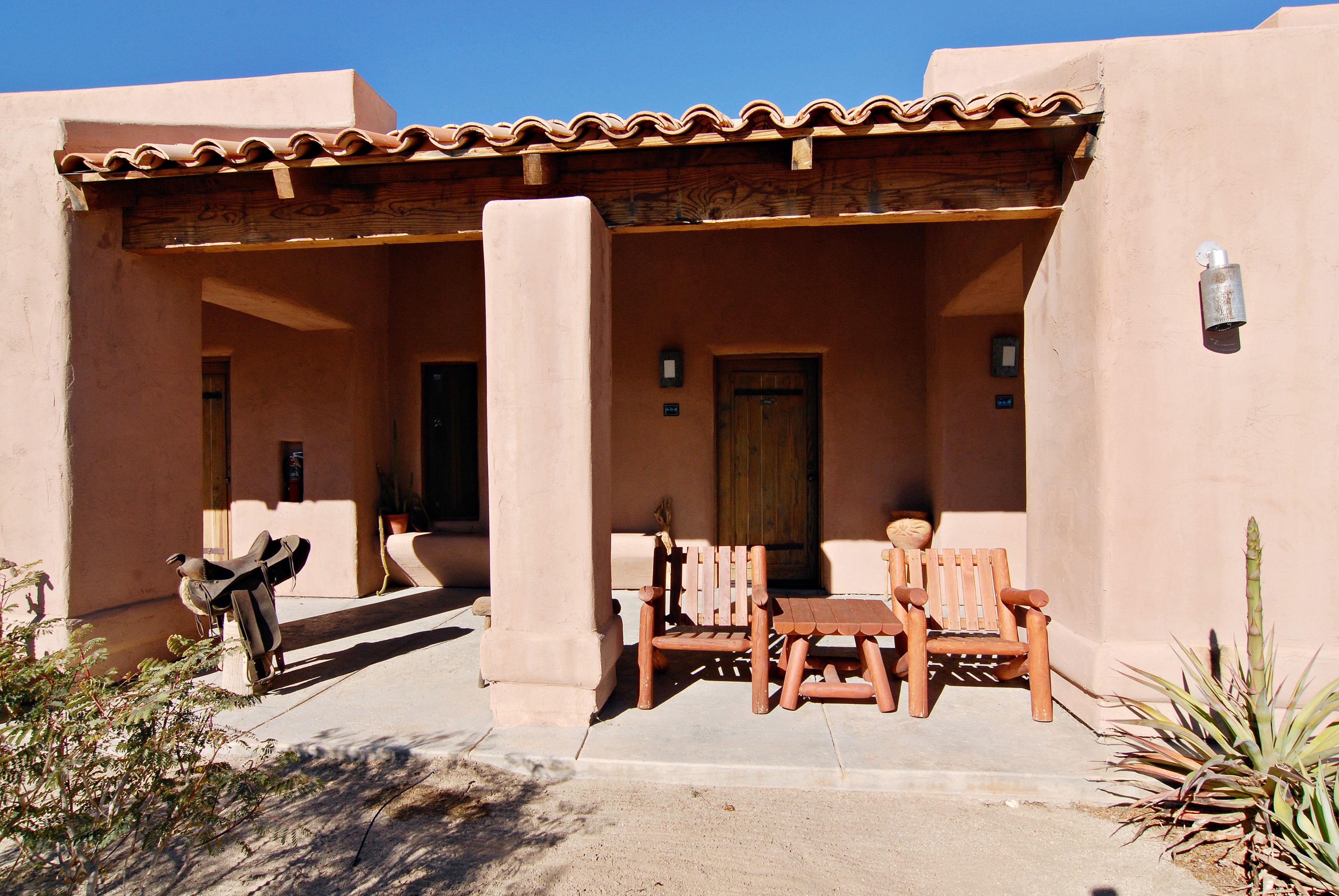 A building with a covered patio area, a wooden bench, and a door.