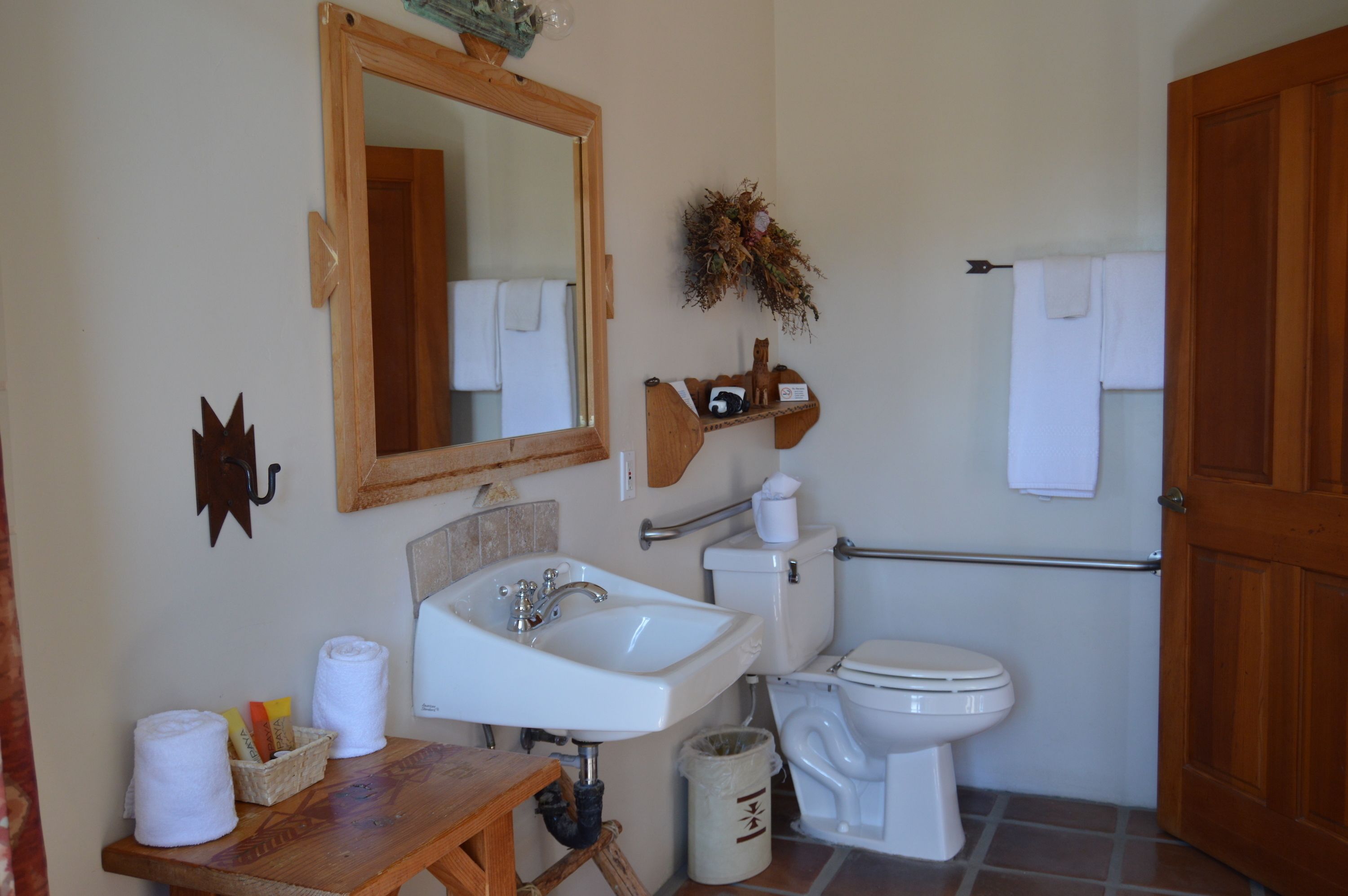 Un baño con tocador de madera, lavamanos blanco, espejo, inodoro y zona de ducha.