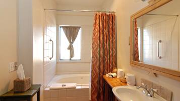 Un baño con bañera, lavamanos, espejo y ventana con cortina.
