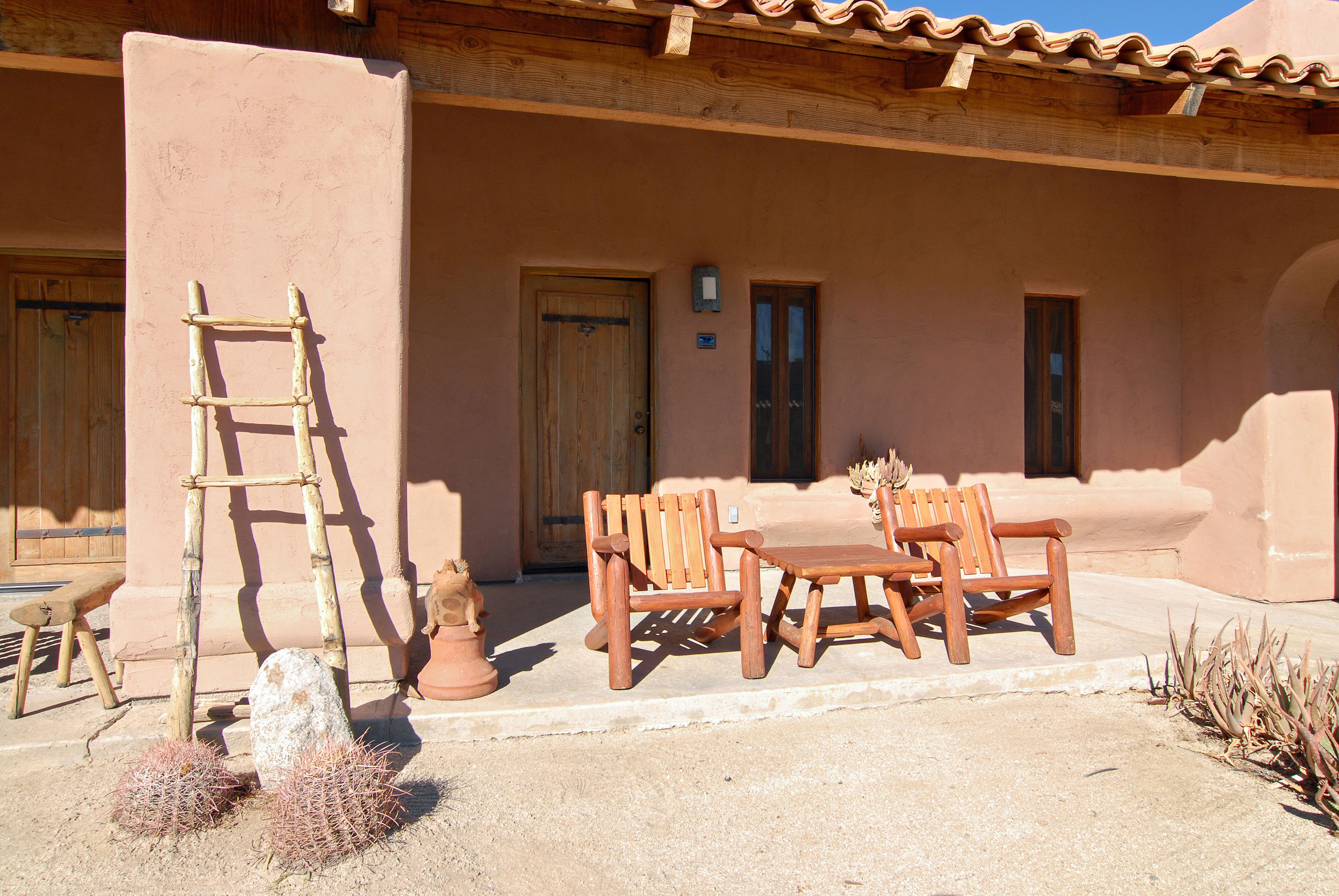 A patio with wooden furniture, a ladder, and a cactus.
