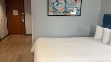 Una habitación de hotel con cama, una puerta y una obra de arte colgada en la pared.