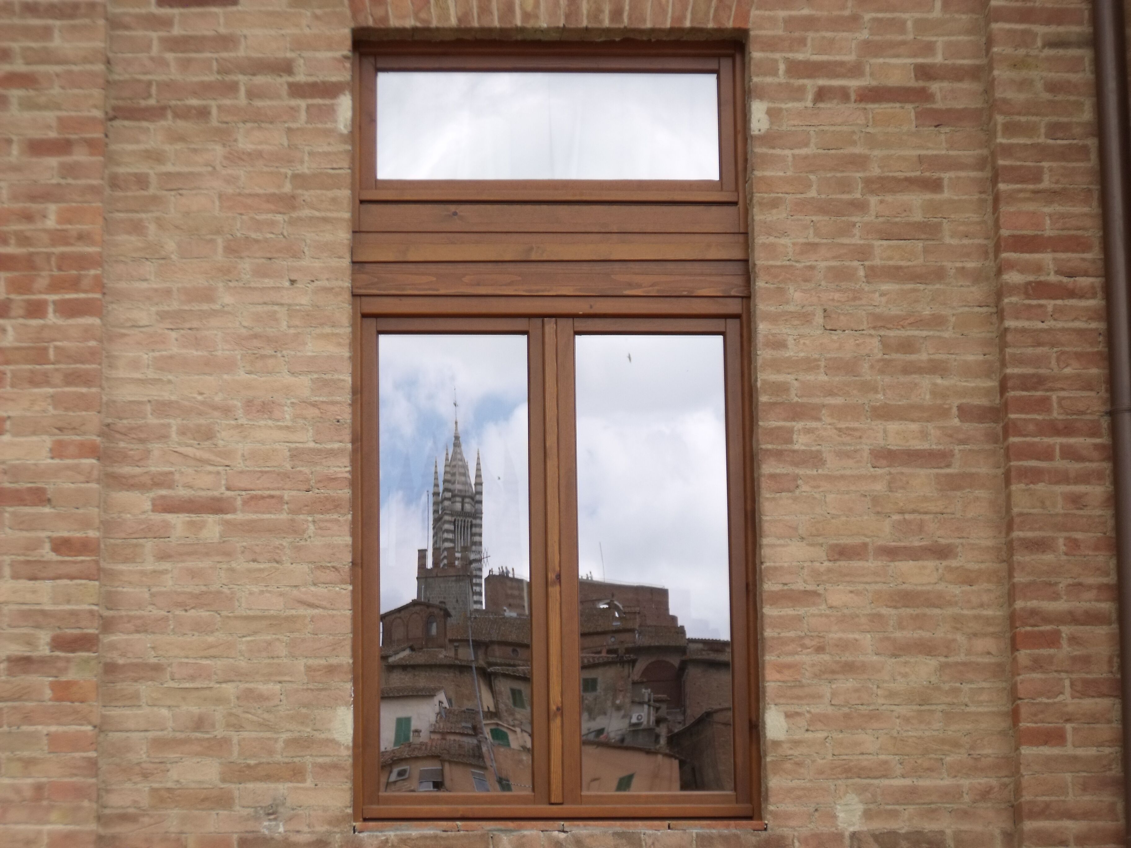 Una ventana con vista a un edificio de ladrillo y una torre.