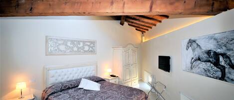 Une chambre à coucher avec un lit, des tables de chevet, une armoire et un grand tableau au mur.