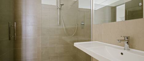 Une salle de bain moderne avec une douche, un lavabo et un miroir.