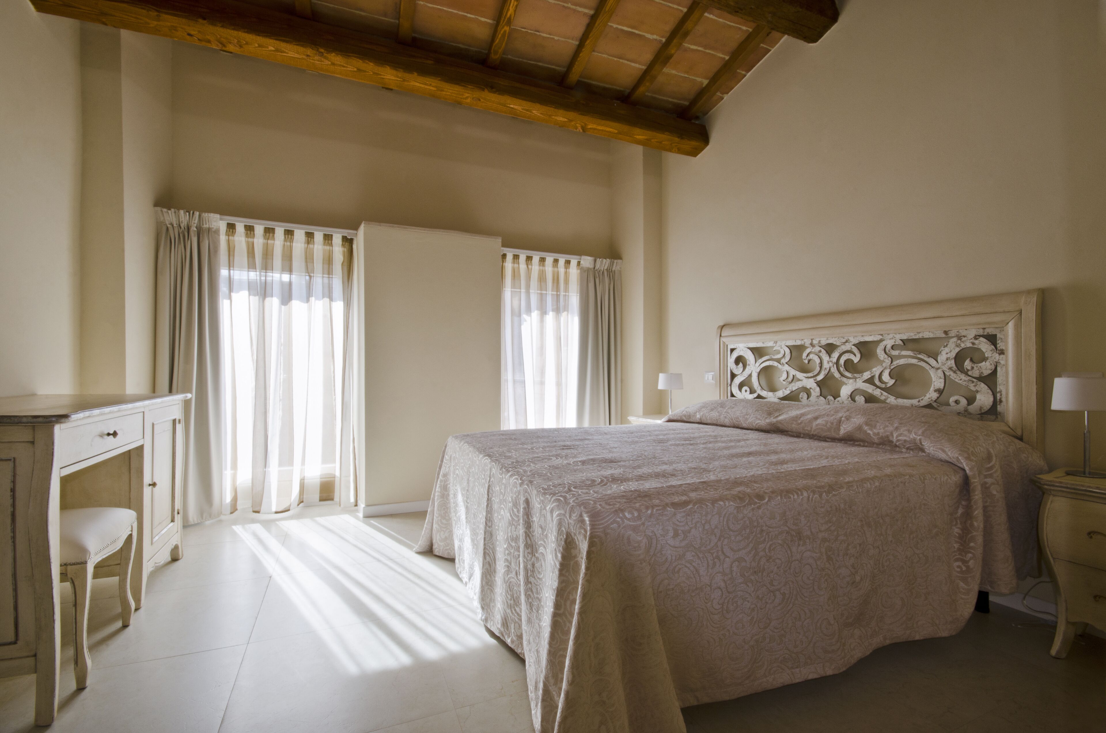 A bedroom with a large bed, a desk, and a chair.
