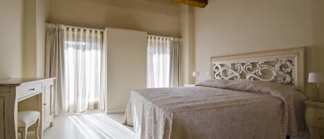 A bedroom with a large bed, a desk, and a chair.