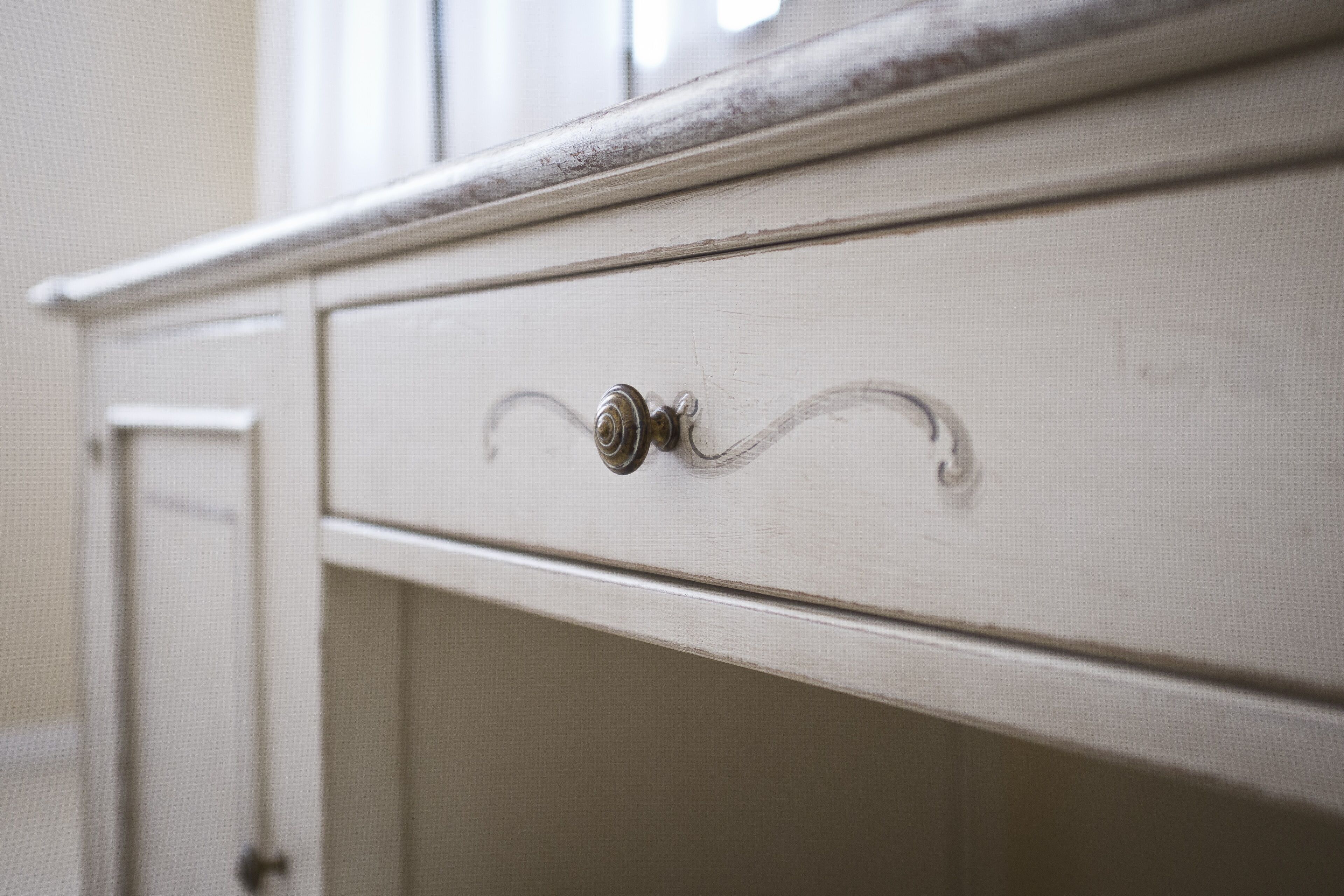 A white dresser with a single drawer, a metal knob, and a visible hinge.