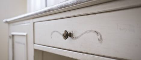 A white dresser with a single drawer, a metal knob, and a visible hinge.