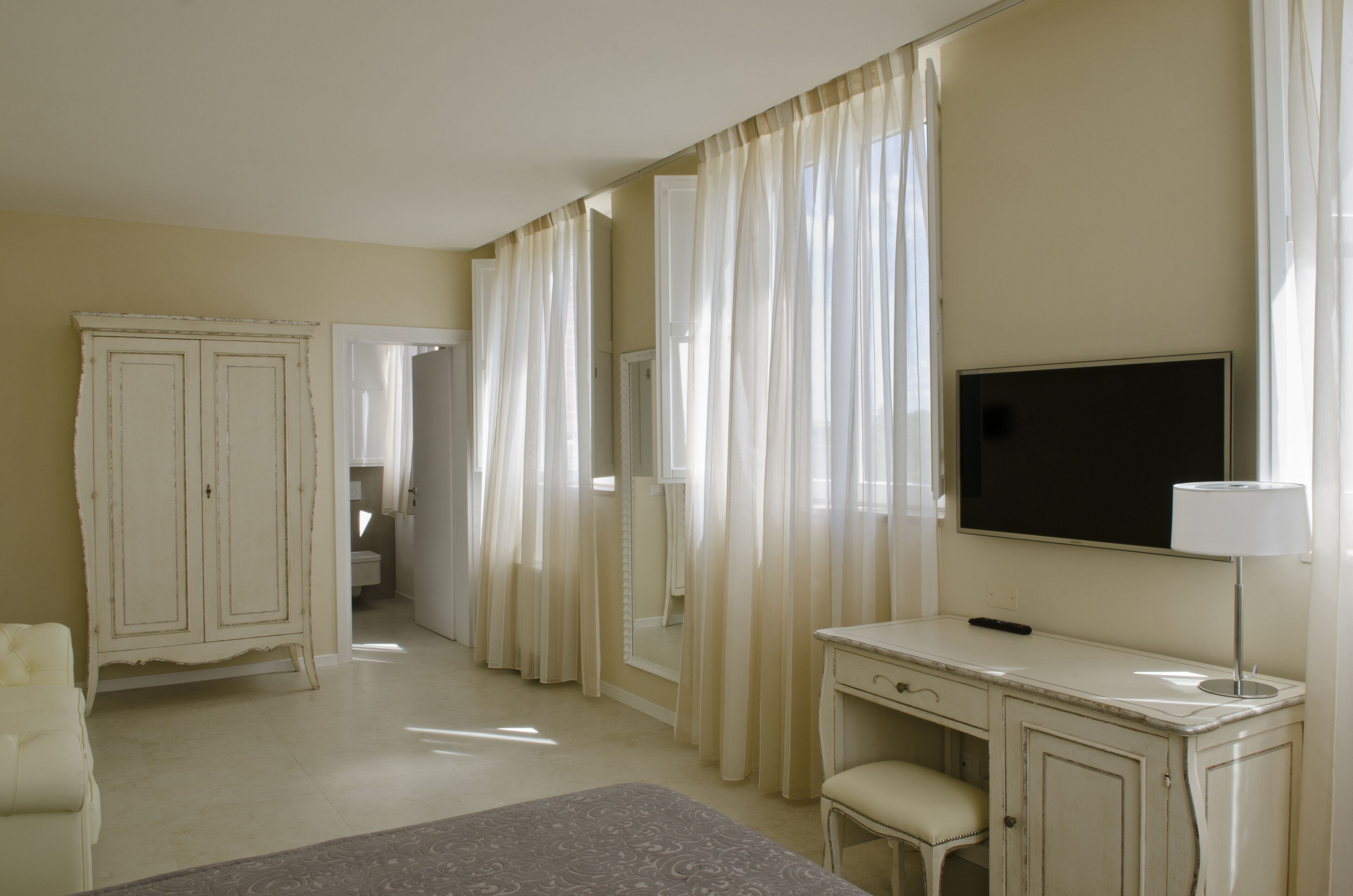 A hotel room with a bed, a desk, a chair, a television, and a wardrobe.