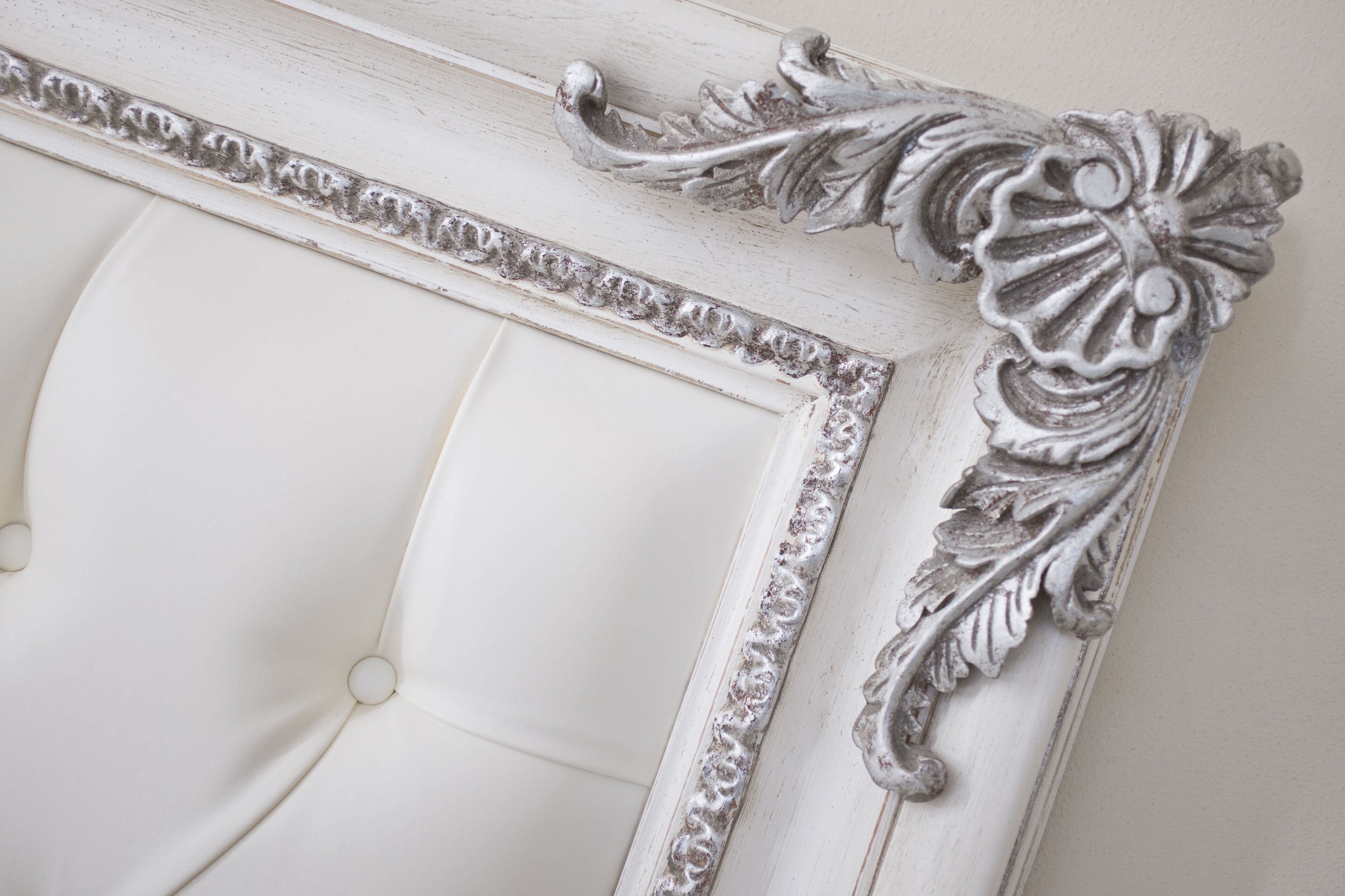 Un cadre photo blanc et décoratif, avec une tête de lit capitonnée.