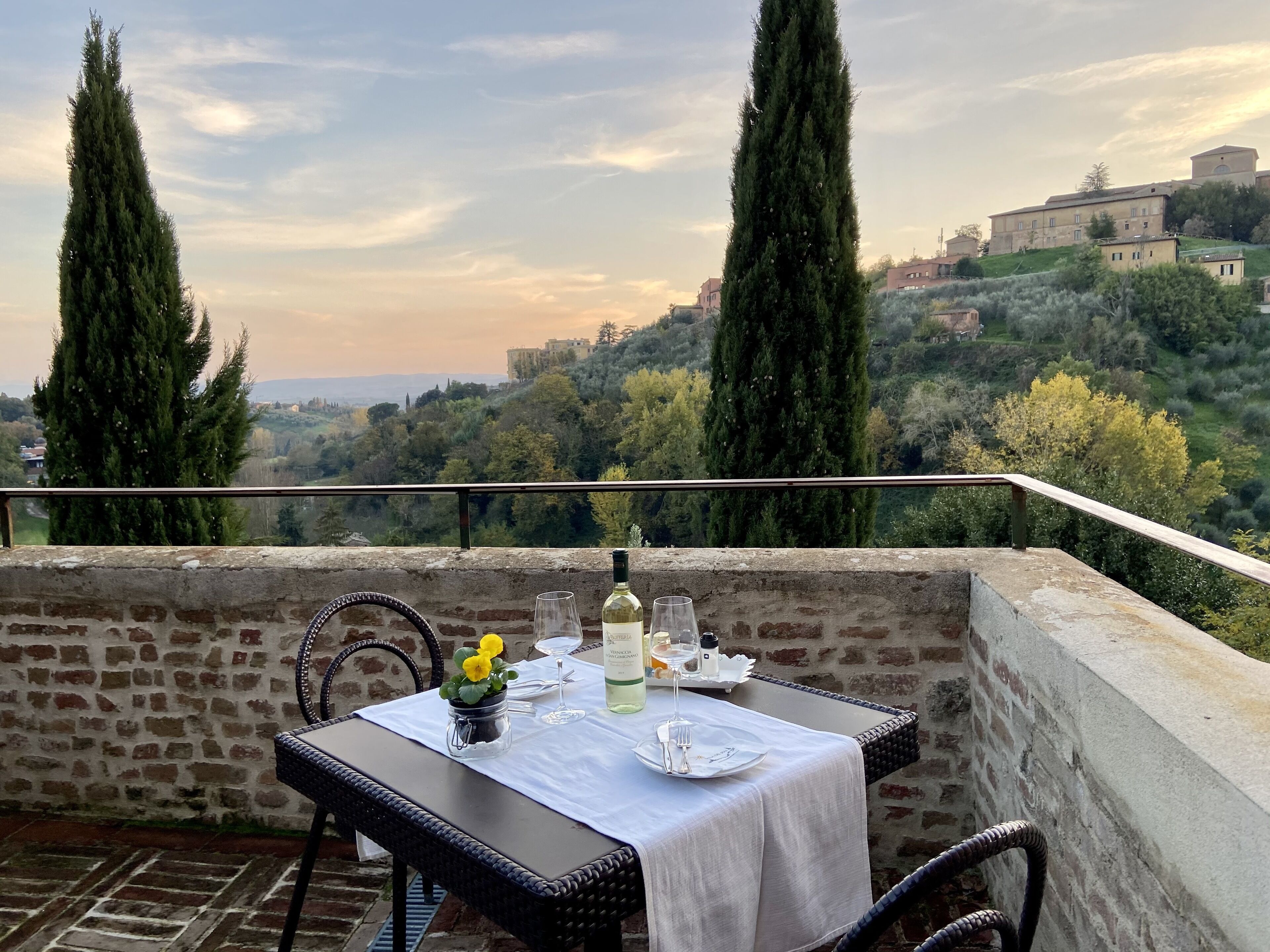 A table set for two with a view of a hillside town.