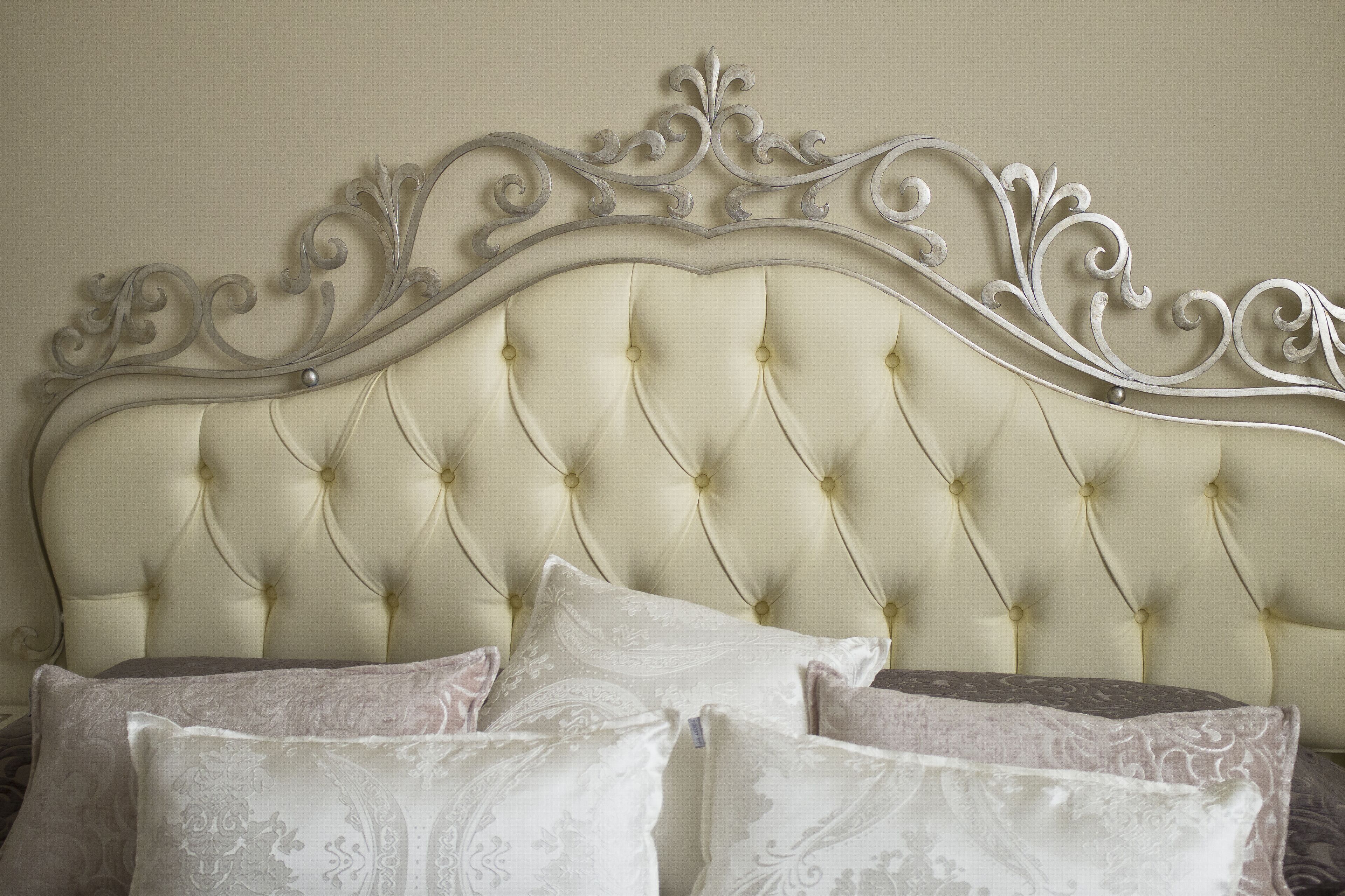 A bed with a tufted headboard and decorative metalwork.