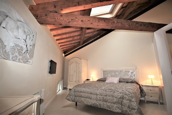 A bedroom with a bed, bedside tables, a wardrobe, and a skylight.