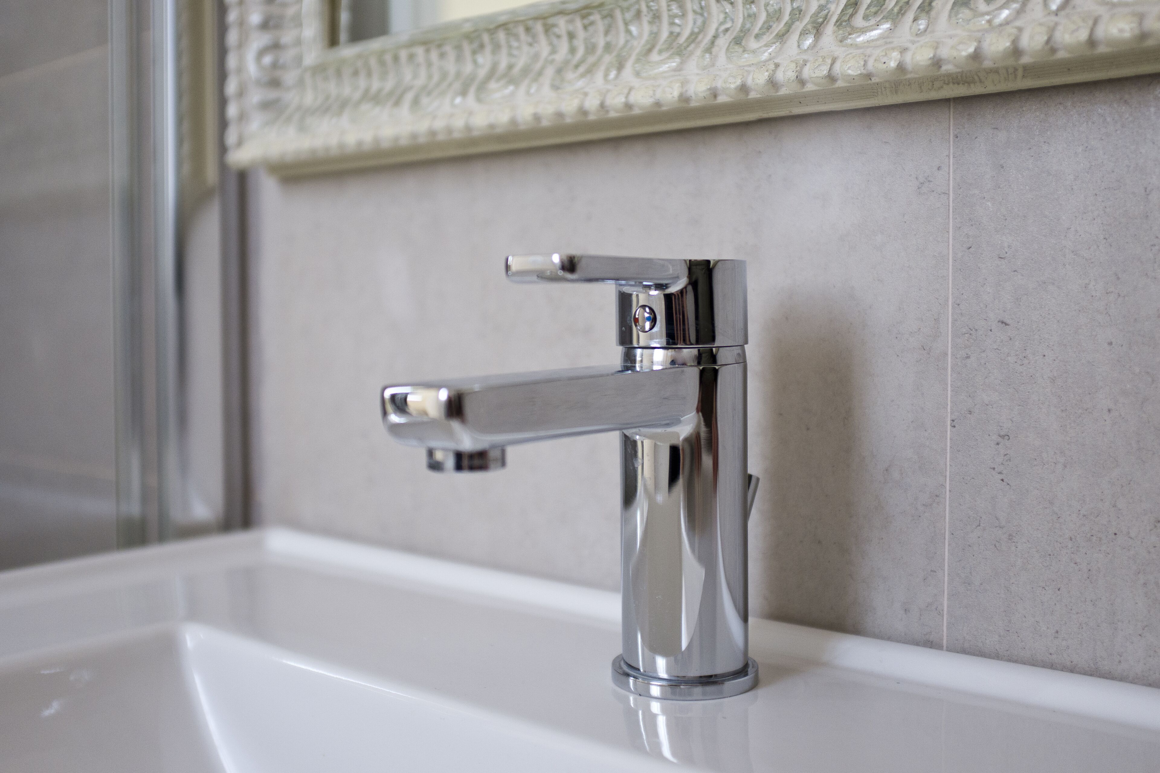 Une salle de bain moderne avec un robinet chromé et un miroir décoratif au-dessus du lavabo.