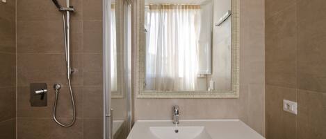 A bathroom with a shower, a sink, and a mirror.
