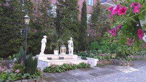 A garden with statues, a lamp post, and various plants. - Park Hotel Turku (Turku)