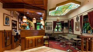 A reception area with a wooden counter, bar stools, and a seating area with round tables and chairs. - Park Hotel Turku (Turku)