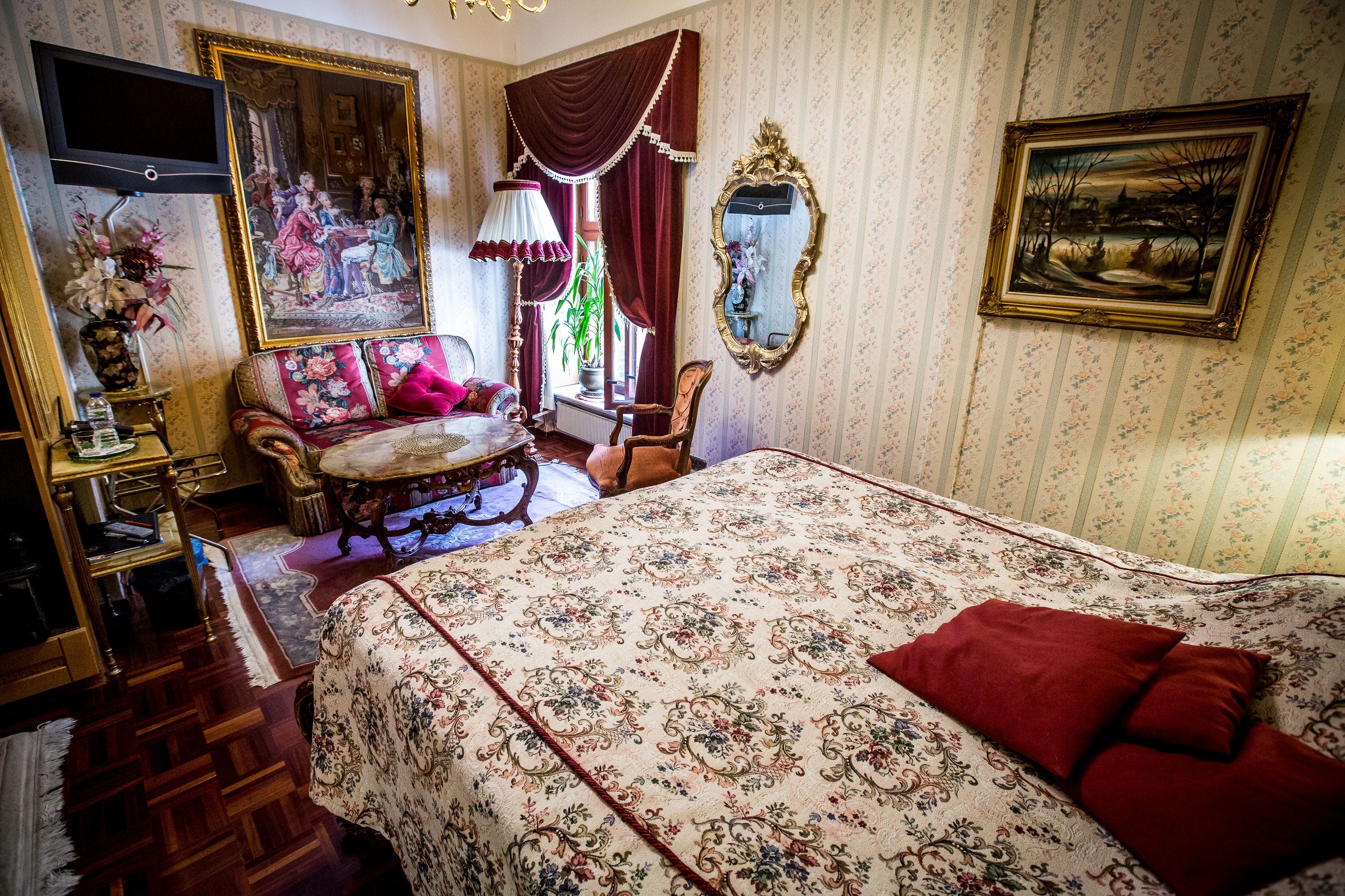 Une chambre classique avec un grand lit, une télévision, un tableau et un miroir.