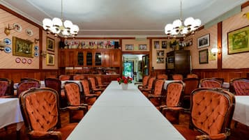 A formal dining room with a long table, multiple chairs, and a chandelier.