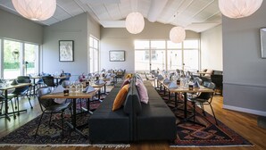 A spacious dining area with multiple tables, chairs, and a central sofa.