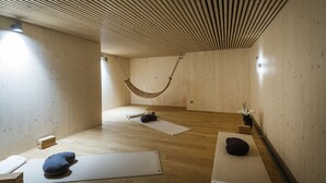 A room with wooden flooring, a hammock, and mats for yoga or meditation.