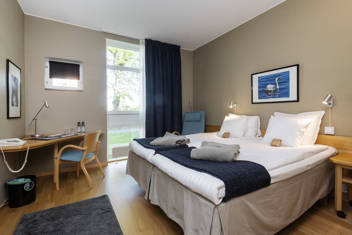 Une chambre à coucher avec un lit, un bureau, une chaise et une fenêtre avec des rideaux.