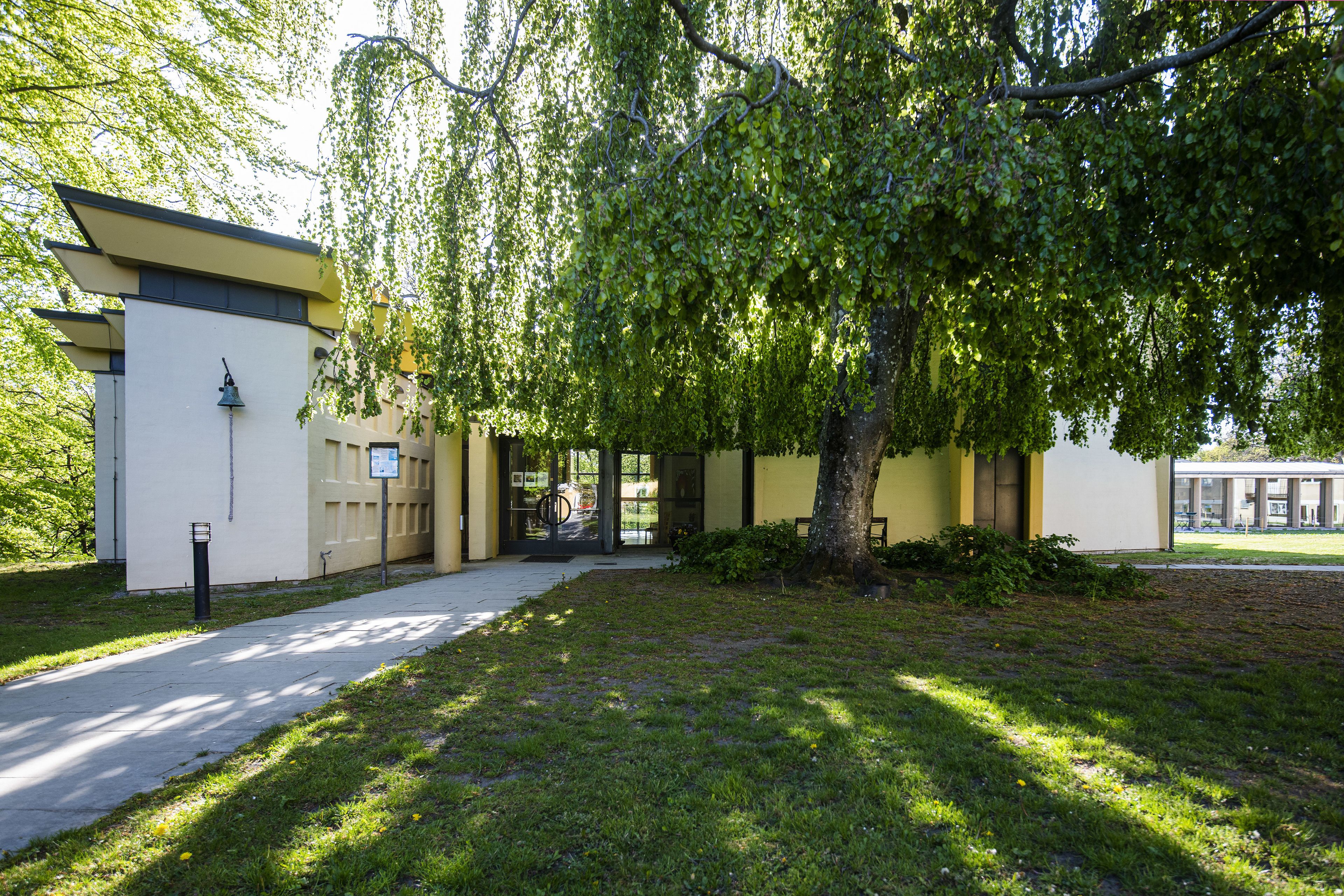 A building with a modern architectural style, a paved pathway, and a well-maintained grassy area.