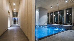 A modern indoor swimming pool with a wooden wall and a stone floor, surrounded by large windows and a high ceiling.