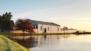 A building with a large pond in front, surrounded by trees and grass. - The Lodge L'Avenir (Stellenbosch)