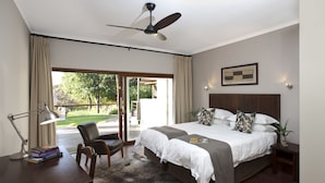 A bedroom with a bed, a desk, a chair, a ceiling fan, and a view of the outdoors. - The Lodge L'Avenir (Stellenbosch)