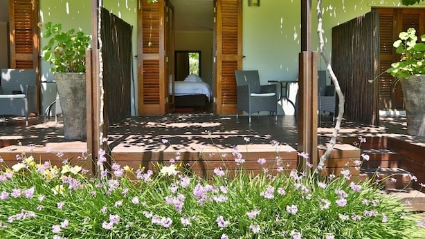 A covered outdoor area with a bed, two chairs, and a table. - The Lodge L'Avenir (Stellenbosch)