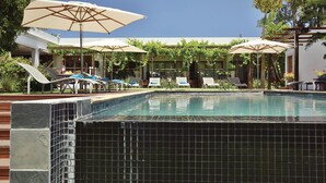 A swimming pool with tiled edges, surrounded by lounge chairs and umbrellas. - The Lodge L'Avenir (Stellenbosch)