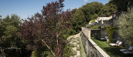 A stone retaining wall with a garden path, lush greenery, and outdoor seating area.