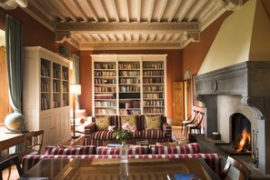 A cozy library with bookshelves, a fireplace, and comfortable seating areas.