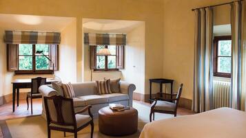 Una habitación de hotel con sofá, dos sillones, una mesita y una cama.