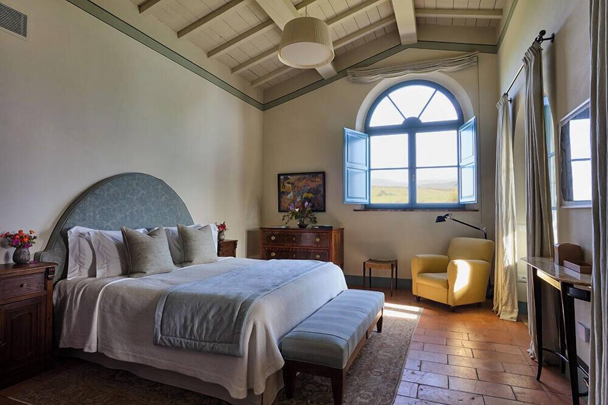 Un dormitorio con una cama grande, un escritorio, una silla y una ventana con vistas al campo.