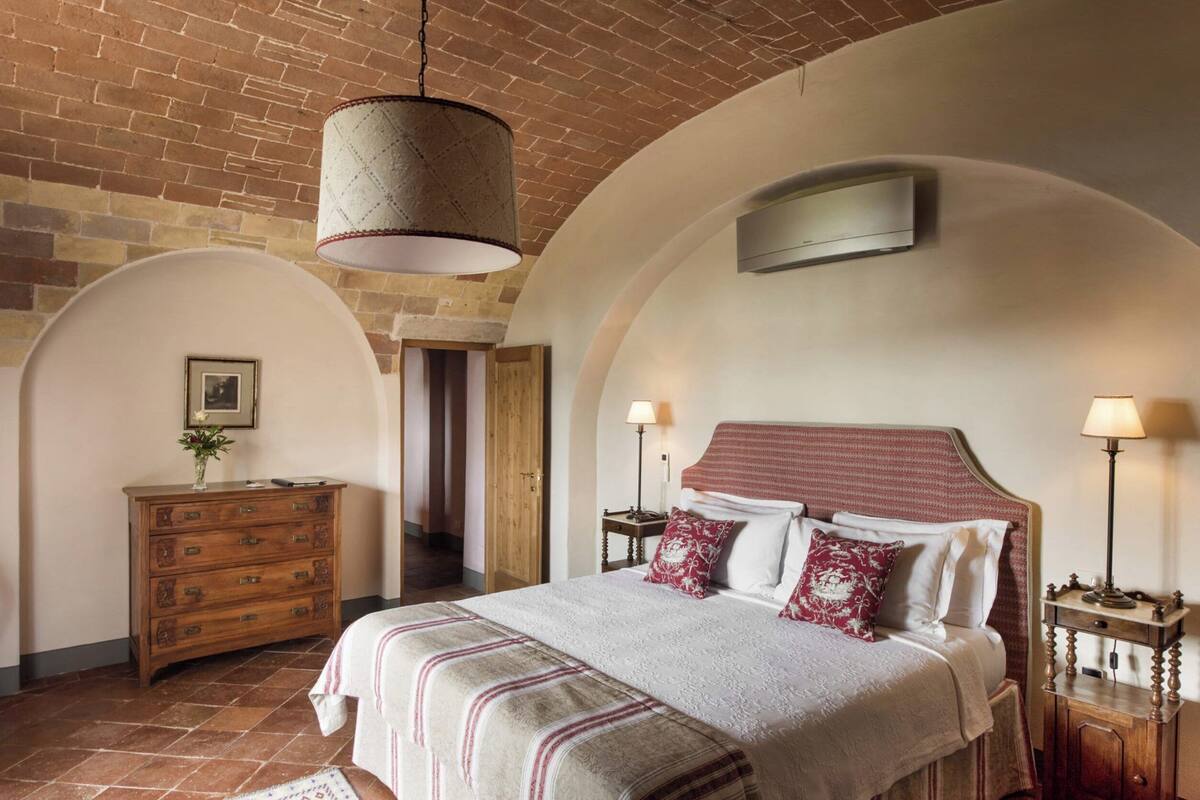 Un dormitorio con una cama grande, cómoda de madera y techo de ladrillo.