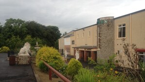 A building with a stone facade and a sign that reads "The Dges." - The Hedges Hotel (Ballymoney)