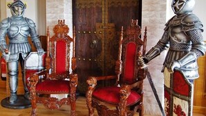 A room with a fireplace, two ornate chairs, and two knight statues. - The Hedges Hotel (Ballymoney)