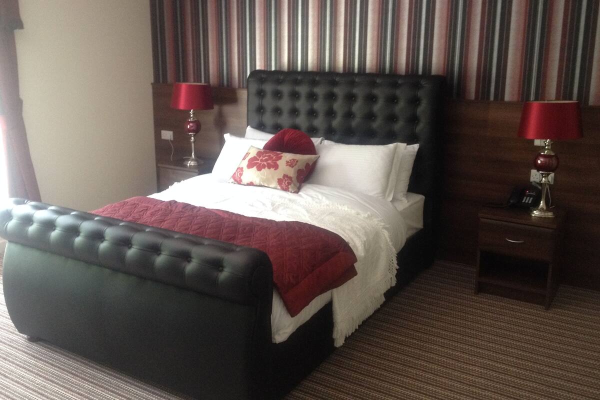 A hotel room with a large bed, two bedside tables, and striped wallpaper.