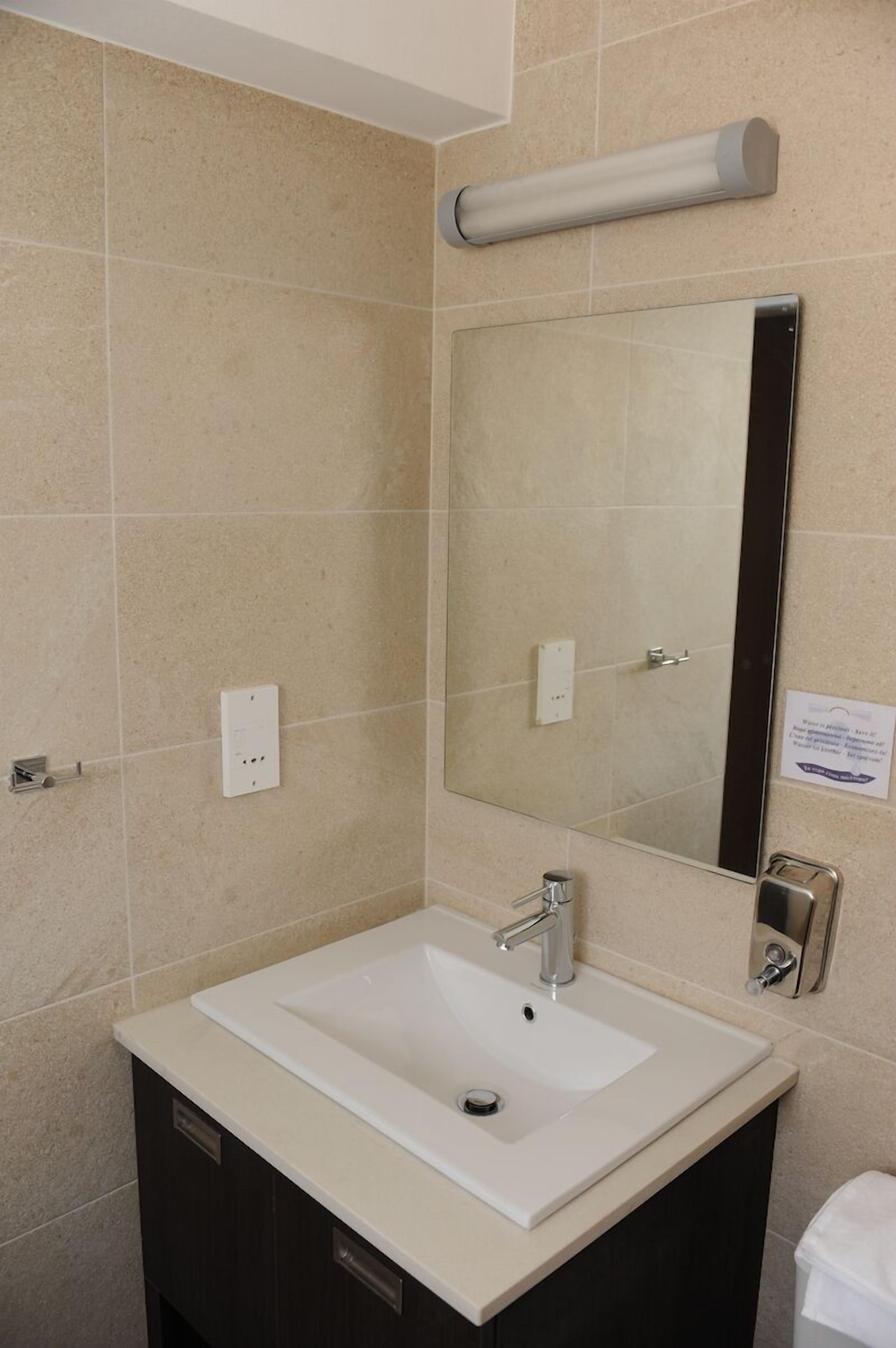 A bathroom with a white sink, a mirror, and a towel rack.